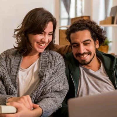 Pärchen schaut gemeinsam auf Laptop im Wohnzimmer – Paarberatung für bessere Kommunikation und Konfliktlösung mit Maximilian König