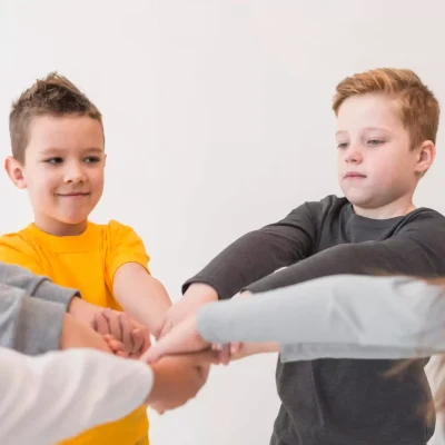 Zufriedene Kinder legen ihre Hände im Teamkreis zusammen – Erfolgserlebnis in Workshops bei Psychologe König.